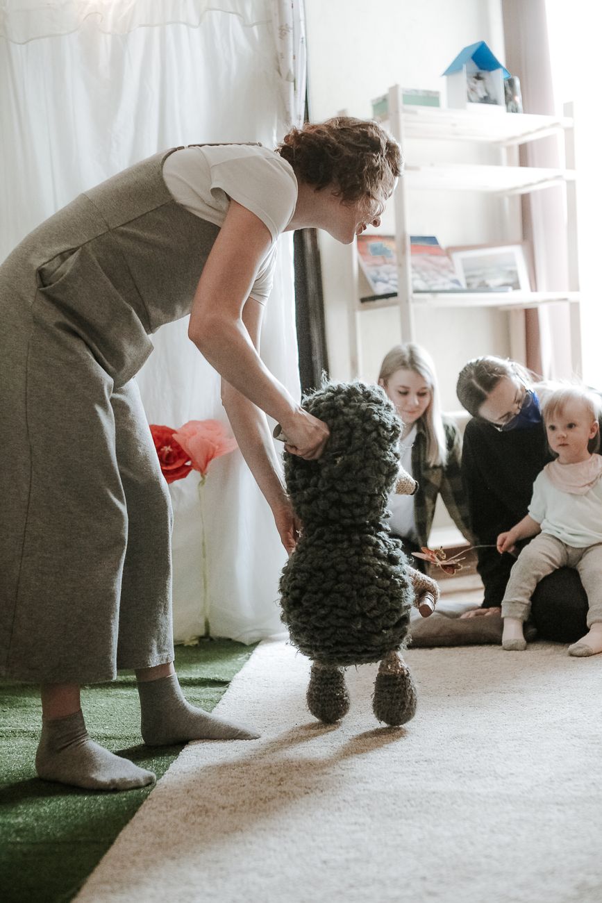 Teacher greeting a parent and child warmly in a cozy nursery entryway