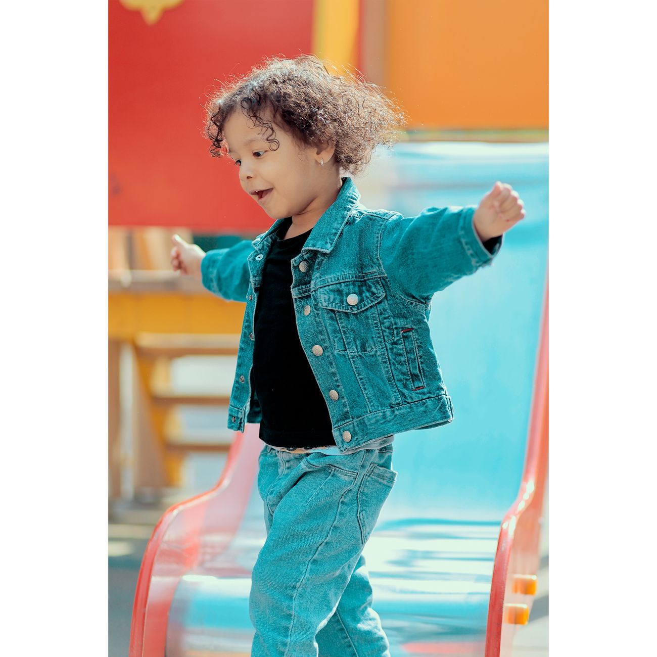 Child running joyfully toward the slide at an outdoor playground