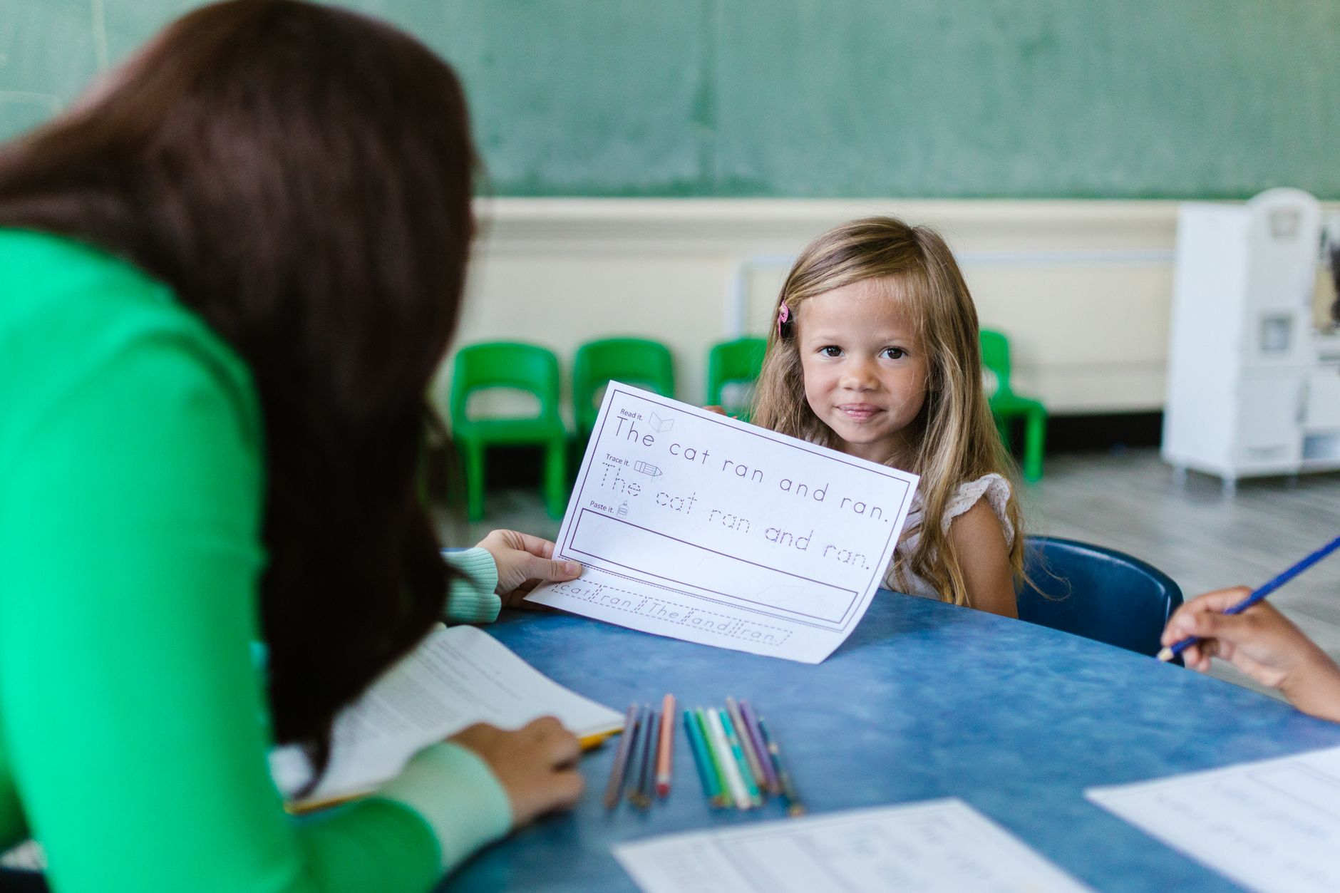 Teacher helping a young girl during a classroom learning activity