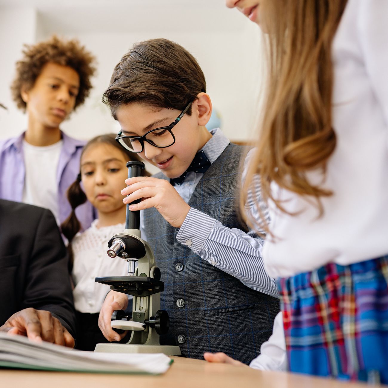 Children exploring a science activity together with a microscope in the classroom